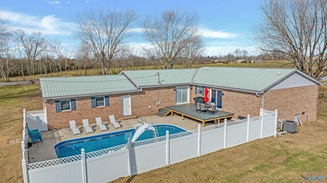 view of swimming pool featuring central air condition unit, a wooden deck, and a yard