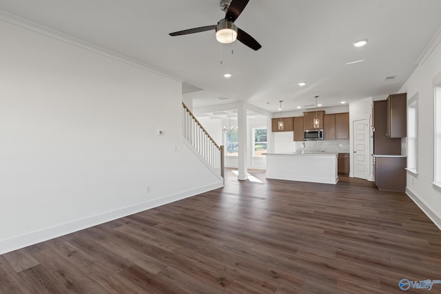 unfurnished living room featuring crown molding, dark wood-type flooring, and ceiling fan