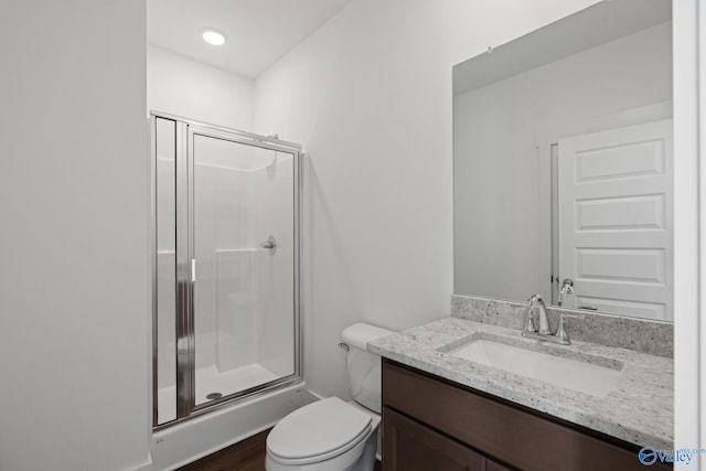 bathroom with vanity, toilet, a shower with shower door, and hardwood / wood-style floors