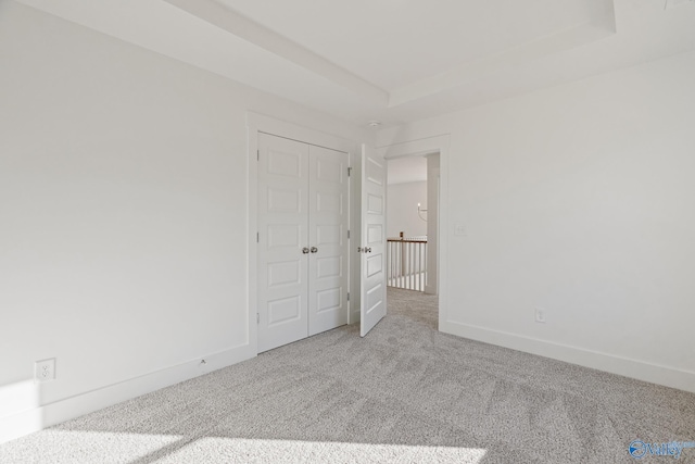 carpeted empty room with a raised ceiling