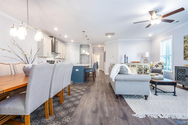 living room with dark hardwood / wood-style flooring, sink, crown molding, and ceiling fan with notable chandelier