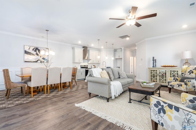 living room featuring ceiling fan with notable chandelier, ornamental molding, and light wood-type flooring