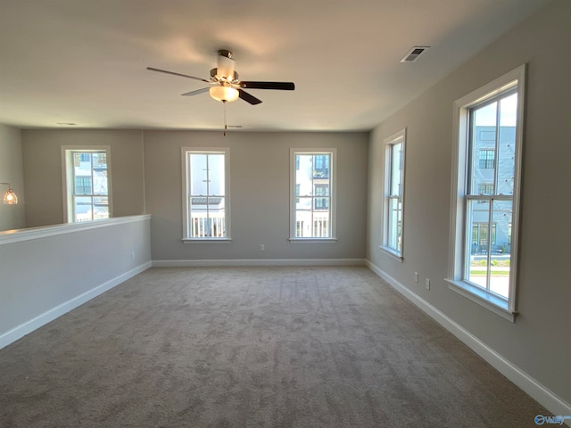 carpeted empty room featuring a wealth of natural light and ceiling fan