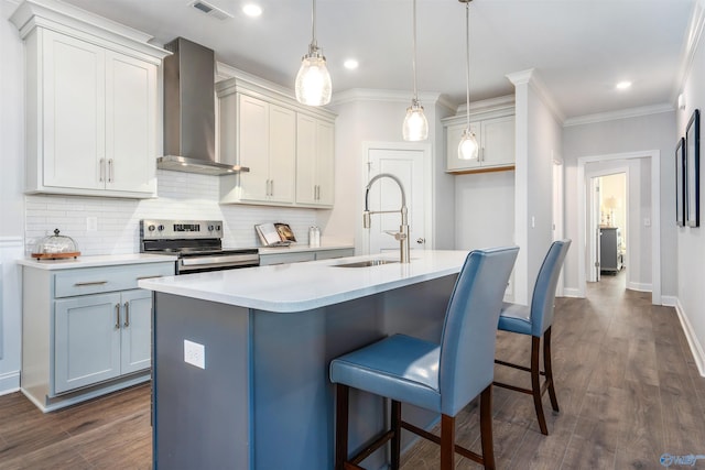 kitchen featuring pendant lighting, sink, stainless steel electric range, a kitchen island with sink, and wall chimney exhaust hood