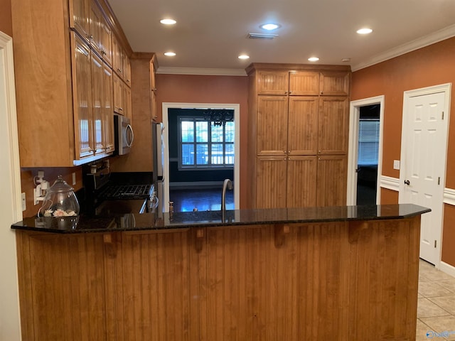 kitchen featuring kitchen peninsula, appliances with stainless steel finishes, and dark stone counters