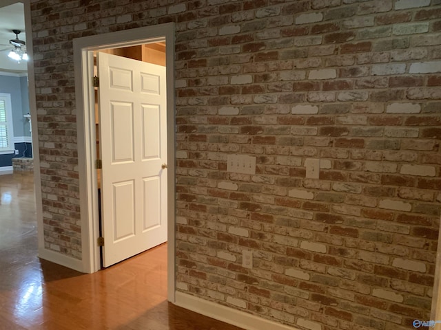 hallway featuring wood-type flooring and brick wall