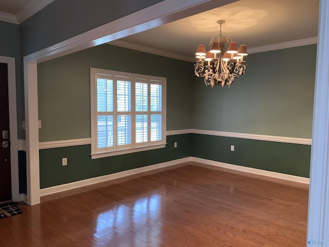 spare room featuring hardwood / wood-style floors, ornamental molding, and a chandelier