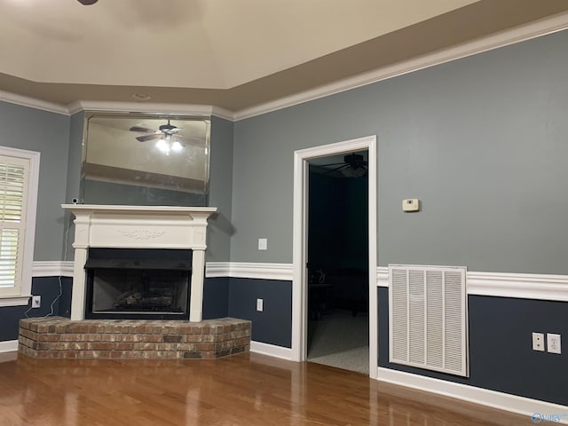 unfurnished living room with hardwood / wood-style floors, vaulted ceiling, a brick fireplace, ceiling fan, and ornamental molding