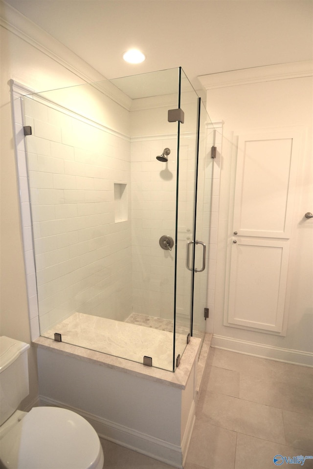 bathroom with tile patterned flooring, toilet, crown molding, and a shower with shower door