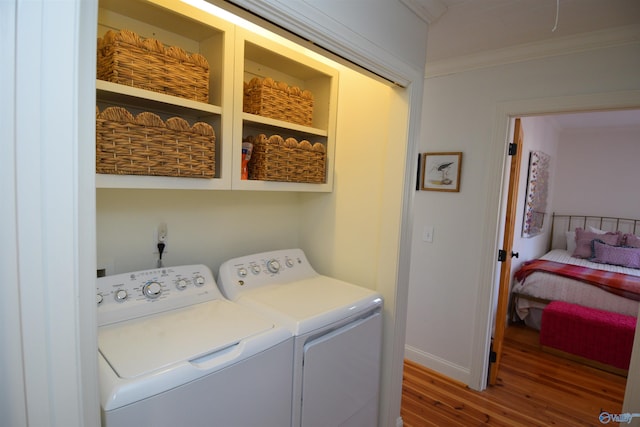 washroom with separate washer and dryer, wood-type flooring, and ornamental molding