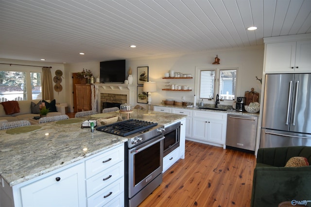 kitchen featuring sink, high quality appliances, ornamental molding, light hardwood / wood-style floors, and white cabinets