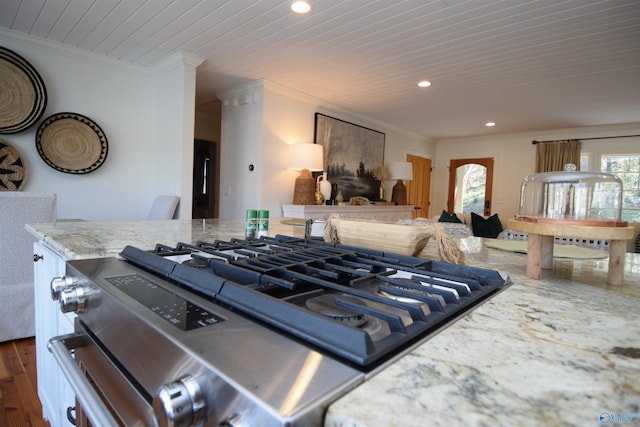 kitchen with gas range, dark hardwood / wood-style flooring, crown molding, and light stone counters