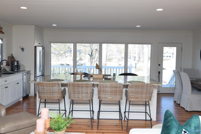 dining space with ornamental molding, sink, and dark wood-type flooring