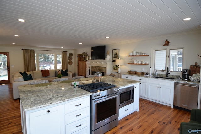 kitchen with sink, crown molding, appliances with stainless steel finishes, white cabinetry, and light stone countertops