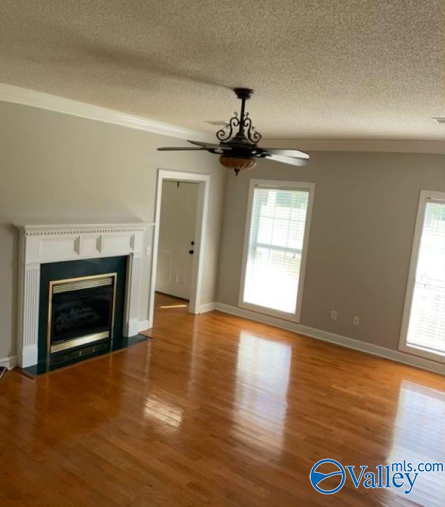 unfurnished living room with crown molding, light wood-type flooring, and a wealth of natural light