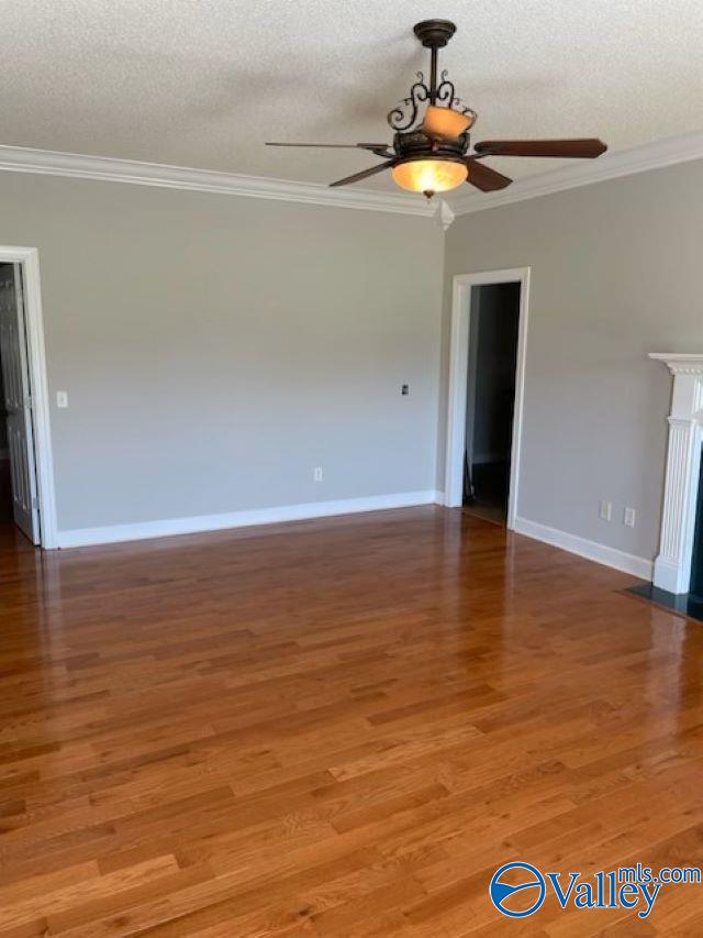 empty room featuring hardwood / wood-style flooring, ceiling fan, ornamental molding, and a textured ceiling