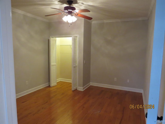 unfurnished bedroom with crown molding, a closet, ceiling fan, and hardwood / wood-style flooring