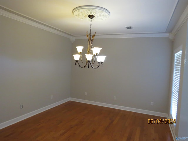 spare room featuring crown molding, wood-type flooring, and a notable chandelier