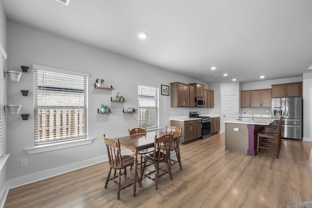 dining space featuring baseboards, light wood finished floors, and recessed lighting