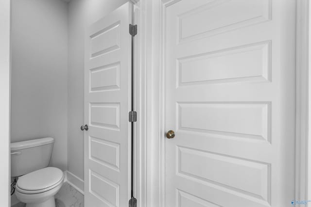 bathroom featuring marble finish floor, toilet, and baseboards