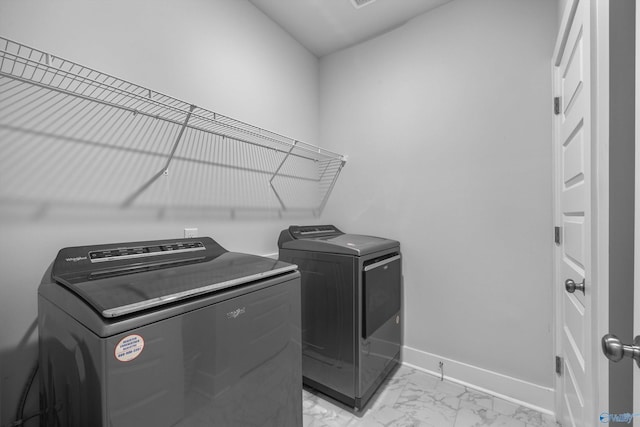 laundry area with laundry area, baseboards, marble finish floor, and washing machine and clothes dryer