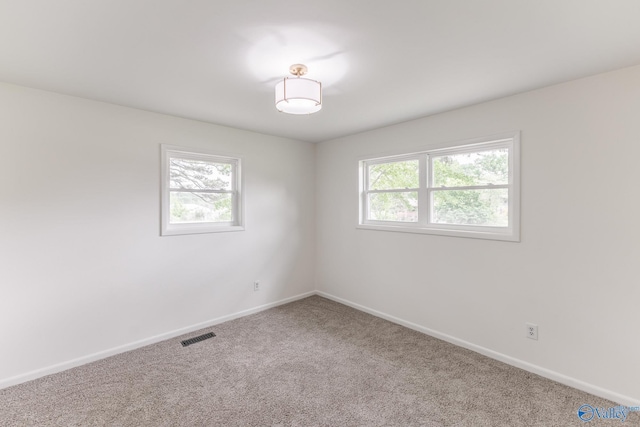 spare room featuring baseboards, visible vents, carpet flooring, and plenty of natural light