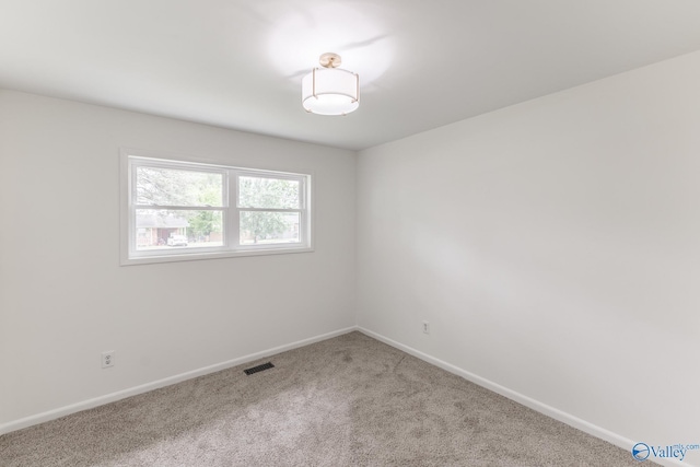 carpeted spare room featuring visible vents and baseboards