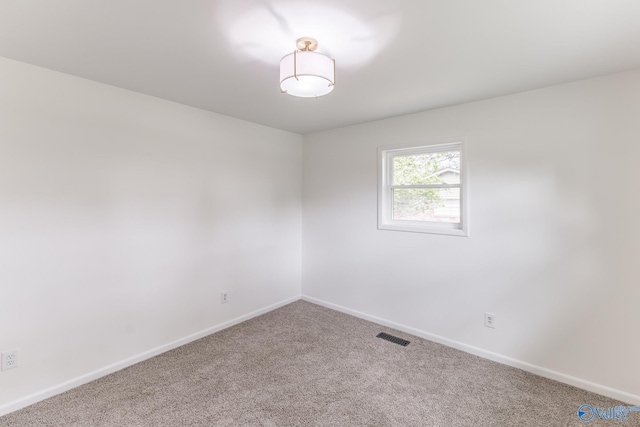 carpeted empty room featuring visible vents and baseboards