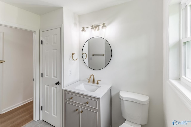 bathroom with wood finished floors, vanity, and toilet