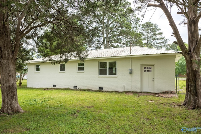 back of house with a yard, brick siding, fence, metal roof, and crawl space