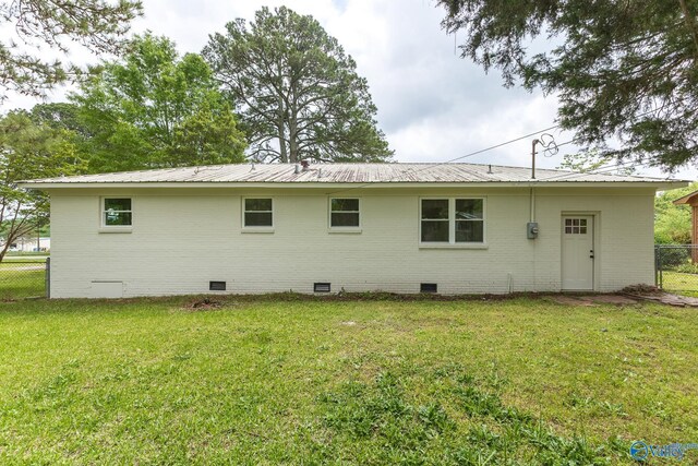 back of house with brick siding, fence, and crawl space