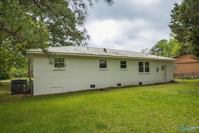 rear view of house featuring fence, central AC unit, a lawn, and crawl space