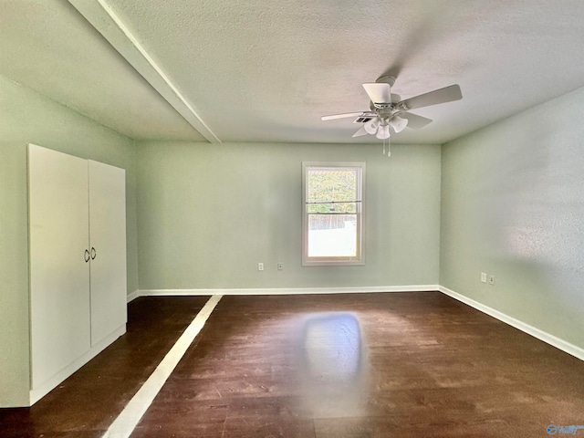 empty room with a textured ceiling, dark wood-type flooring, and ceiling fan