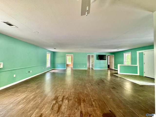 unfurnished living room with a textured ceiling and dark hardwood / wood-style flooring