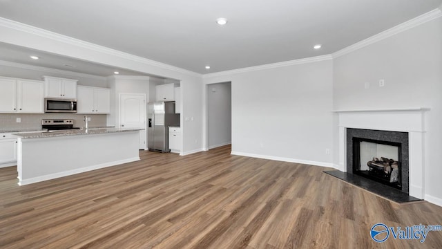 unfurnished living room with light wood-type flooring, crown molding, and sink