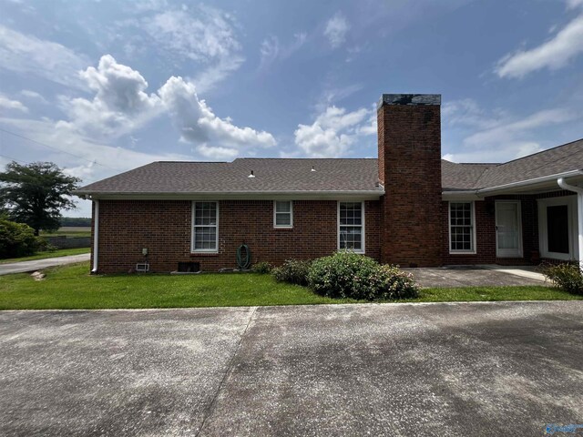 16052 Court St, Moulton, AL 35650 - view of home's exterior featuring brick siding, a lawn, a chimney, and a shingled roof