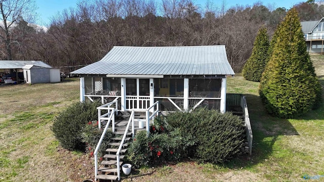 view of front facade with metal roof, stairway, a front yard, and a sunroom