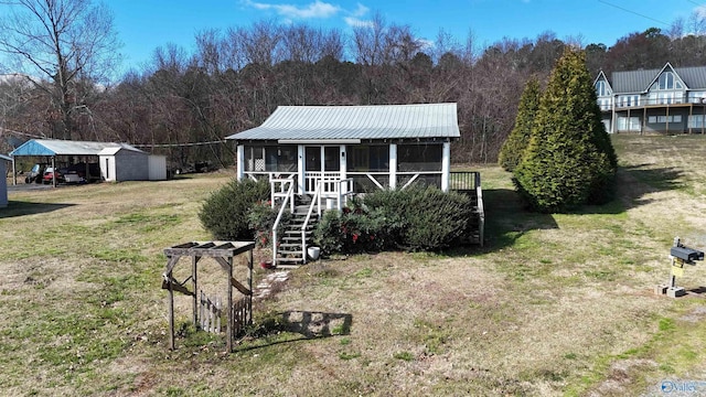 view of front of home with metal roof, an outbuilding, a front lawn, and stairway