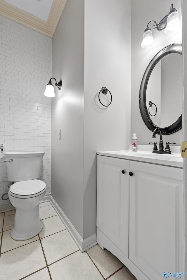 bathroom with toilet, ornamental molding, tile walls, tile patterned floors, and vanity