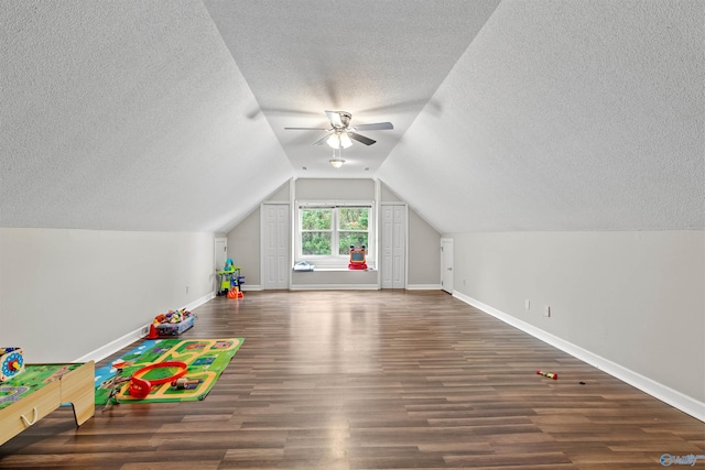 playroom with wood finished floors, vaulted ceiling, ceiling fan, baseboards, and a textured ceiling