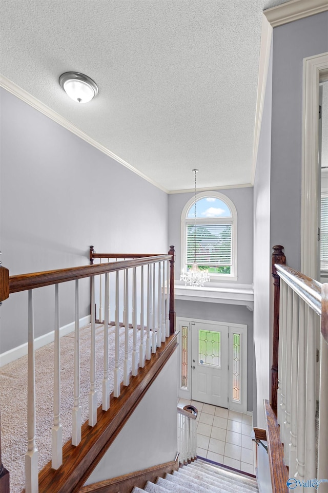 foyer featuring ornamental molding, a textured ceiling, a notable chandelier, and tile patterned floors
