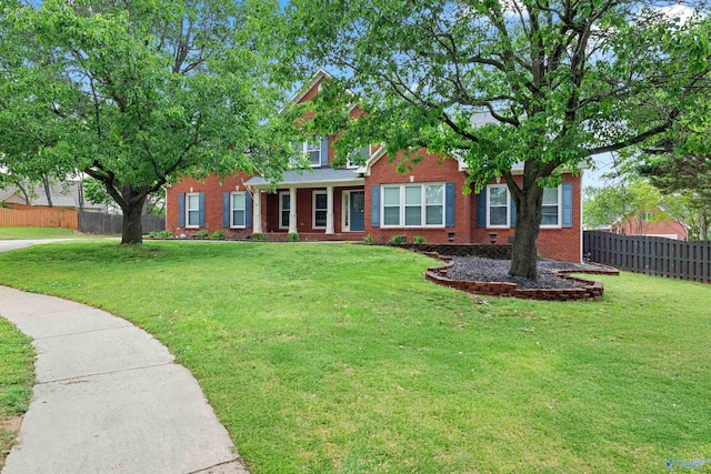 view of front of home featuring a front yard, fence, and brick siding