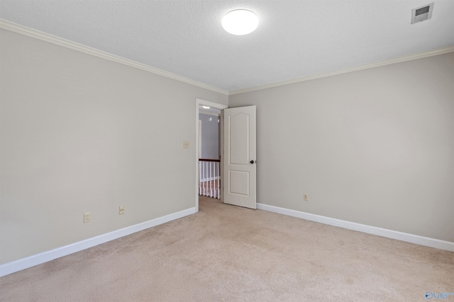 spare room with light colored carpet, baseboards, visible vents, a textured ceiling, and crown molding