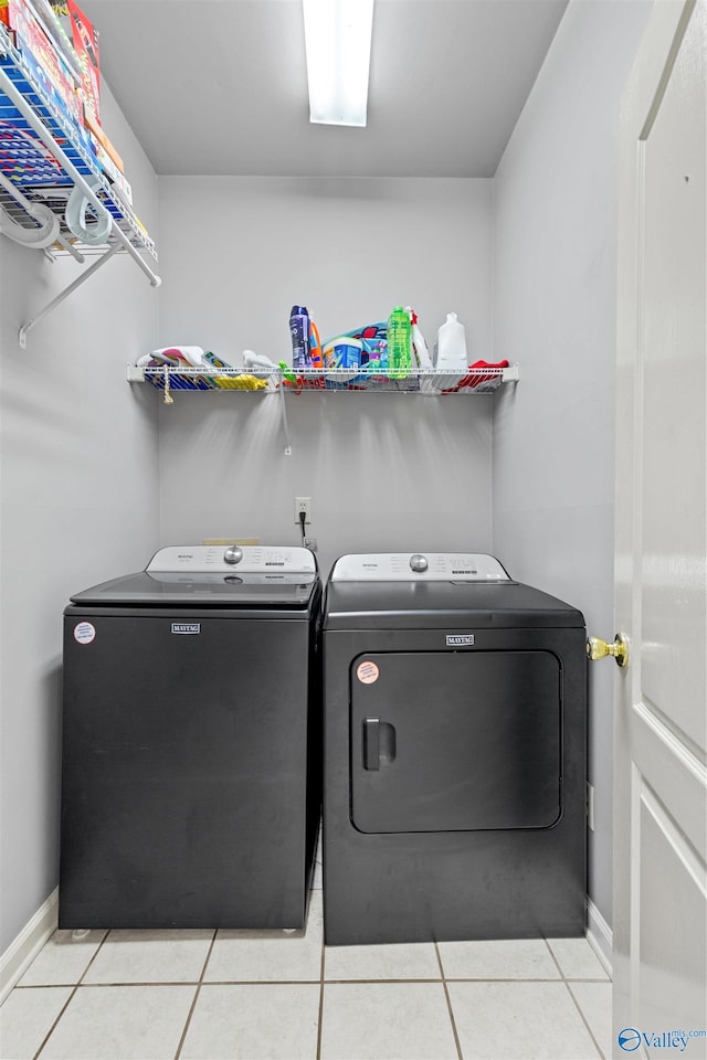 laundry area with baseboards, light tile patterned floors, washer and clothes dryer, and laundry area
