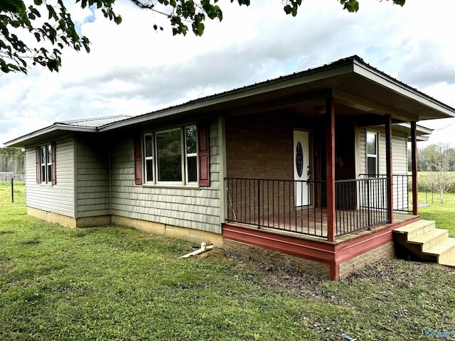 view of property exterior featuring covered porch, metal roof, and a lawn
