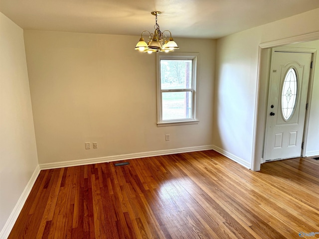 entrance foyer with baseboards, visible vents, wood finished floors, and a notable chandelier