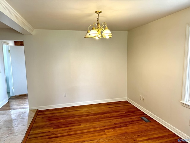 unfurnished room featuring visible vents, an inviting chandelier, light wood-style floors, and baseboards