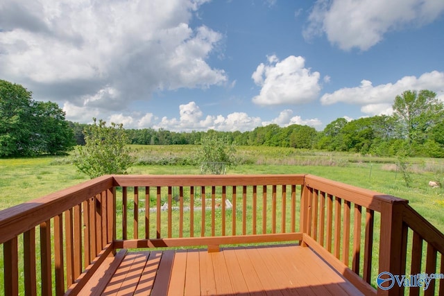 wooden terrace featuring a rural view and a yard