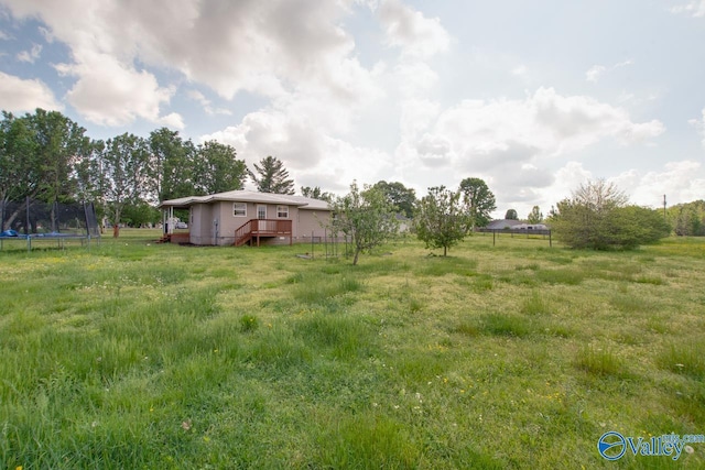 view of yard with a wooden deck and a trampoline