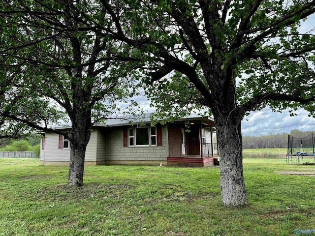 view of front of home featuring a porch, a front yard, and a trampoline
